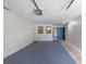 Spacious garage with painted floor, textured walls, and blue door at 2980 Haines Bayshore Rd # 105, Clearwater, FL 33760
