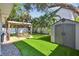 A backyard featuring a pergola-covered patio, shed, and well-manicured lawn at 3127 W Oakellar Ave, Tampa, FL 33611