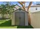 Backyard view of a storage shed with double doors on a fresh green lawn and white fence at 3127 W Oakellar Ave, Tampa, FL 33611