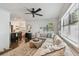Open-concept living room featuring hardwood floors, neutral furniture, bright natural light, and a view into the kitchen at 3127 W Oakellar Ave, Tampa, FL 33611