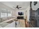 Bright living room features hardwood floors, neutral sofa, ceiling fan, and a large window with natural light at 3127 W Oakellar Ave, Tampa, FL 33611