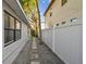 View of the side yard showcasing a stone paver walkway and fresh gravel between the home and white fence at 3127 W Oakellar Ave, Tampa, FL 33611