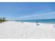 This beach view showcases the white sands and pristine, clear blue waters under a sunny sky at 340 Bay Plaza, Treasure Island, FL 33706