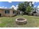 Large backyard featuring a classic brick fire pit and lush greenery, creating a cozy outdoor space at 3707 Cambridge St, New Port Richey, FL 34652