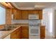 Kitchen with stainless steel sink, wood cabinets, a microwave, an oven, and tile flooring at 3707 Cambridge St, New Port Richey, FL 34652