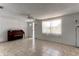 Bright living room featuring tile floors, white walls, a piano, and natural light from a window at 3707 Cambridge St, New Port Richey, FL 34652
