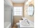 Cozy bathroom featuring a shower-tub combo, a ceramic sink and a modern light fixture at 3907 W Azeele St, Tampa, FL 33609