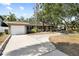Inviting single-story home with a long driveway, attached garage, and a lush green lawn surrounded by mature trees at 3907 W Azeele St, Tampa, FL 33609