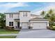 Two-story home featuring a three-car garage, landscaped front yard, and a light gray stucco exterior at 4021 Harvest Hearth Pl, Plant City, FL 33565