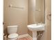 Powder room featuring a pedestal sink, and a toilet, accented by neutral wall paint and wood-look flooring at 4503 Legacy Park Dr, Tampa, FL 33611