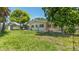Expansive backyard with lush green lawn, mature trees, and exterior view of the home's architecture at 4720 Coronado S Way, Gulfport, FL 33711