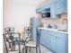 Compact kitchen featuring blue cabinets, stainless appliances, and glass top dining table at 7542 Armand Cir, Tampa, FL 33634