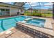 This screened-in pool features a spa and stone tile details, creating a perfect outdoor oasis at 10811 Providence Oaks Dr, Riverview, FL 33578