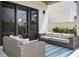 Modern patio with wicker furniture, a blue striped rug, and sliding glass doors at 131 Forest Hills Dr, Redington Shores, FL 33708