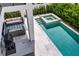 Aerial view of a modern pool area with a spa and stylish outdoor furniture at 131 Forest Hills Dr, Redington Shores, FL 33708