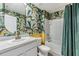 Tropical themed bathroom with vibrant wallpaper, modern fixtures and a combined tub/shower at 13304 Mylion Way, Spring Hill, FL 34610