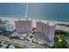 Aerial view of pink high-rise condominiums featuring red tennis courts and beautiful beach at 1340 Gulf Blvd # 8C, Clearwater Beach, FL 33767