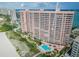 Aerial view of a tall pink condo building near beach access and an outdoor pool at 1340 Gulf Blvd # 8C, Clearwater Beach, FL 33767