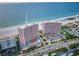 Aerial view of a pink condo building on the beach with tennis courts and well maintained landscaping at 1340 Gulf Blvd # 8C, Clearwater Beach, FL 33767