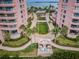Aerial view of condo community, revealing lovely green spaces, walkways, and luxurious pink-toned buildings at 1340 Gulf Blvd # 8C, Clearwater Beach, FL 33767