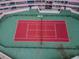 Overhead shot of a red and green tennis court with a net in a complex, ready for a match at 1340 Gulf Blvd # 8C, Clearwater Beach, FL 33767