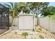 Backyard shed in a gravel area with a black post light, surrounded by trees, shrubs and a fence at 1517 60Th S St, Gulfport, FL 33707