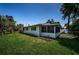 Charming home exterior featuring a screened-in porch and well-maintained lawn with beautiful landscaping at 1700 Shore Acres Ne Blvd, St Petersburg, FL 33703