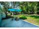 Backyard featuring well-maintained lawn, shade trees, picnic table with sun umbrella, and mature landscaping at 2121 Dodge St, Clearwater, FL 33760