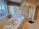 Bright bathroom featuring a large tub with jets, tiled surround, and glass enclosed shower at 2210 Bayou Dr, Holiday, FL 34691