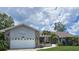 Single-story home with a two-car garage and beautiful landscaping including palm trees at 2210 Bayou Dr, Holiday, FL 34691