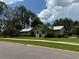 Charming home featuring a well-manicured lawn, mature trees, and an attached two-car garage at 2215 Toniwood Ln, Palm Harbor, FL 34685