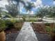 Lush front yard with a stone pathway bordered by diverse plants leading to the home's entrance at 2215 Toniwood Ln, Palm Harbor, FL 34685