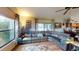 Inviting living room features hardwood floors, a leather sofa, and windows overlooking the outdoor pool area at 2215 Toniwood Ln, Palm Harbor, FL 34685