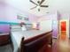 Bedroom with purple walls, wood floors, ceiling fan, and a comfortable bed with soft gray linens at 22804 Willow Lakes Dr, Lutz, FL 33549