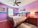 Bedroom with purple walls, wood floors, a ceiling fan, and a comfortable bed with soft gray linens at 22804 Willow Lakes Dr, Lutz, FL 33549
