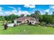 Beautiful home exterior with a well-manicured lawn, large driveway, screened garage, and lush landscaping at 23075 Hayman Rd, Brooksville, FL 34602