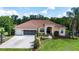 Beautiful home exterior with a well-manicured lawn, large driveway, screened garage, and lush landscaping at 23075 Hayman Rd, Brooksville, FL 34602