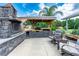 View of the outdoor kitchen and entertaining area with grill and fireplace at 23075 Hayman Rd, Brooksville, FL 34602