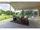View of covered patio seating area and grill with screened pool enclosure and spacious green yard at 23075 Hayman Rd, Brooksville, FL 34602