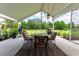 View of covered patio area with table and grill overlooking spacious green lawn at 23075 Hayman Rd, Brooksville, FL 34602