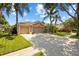Single-Gathering home featuring a well-manicured lawn, mature palms, and a two-car garage, set against a backdrop of blue sky at 2511 Groveway Dr, Valrico, FL 33596