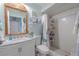 Bright bathroom features a vanity, decorative mirror, toilet and tiled shower with curtain at 2533 Blossom Lake Dr, Holiday, FL 34691