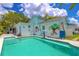 A turquoise pool is surrounded by tropical murals and landscaping, offering a relaxing backyard oasis at 2533 Blossom Lake Dr, Holiday, FL 34691