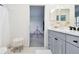 Bright bathroom vanity with double mirrors and gray cabinets leads to another room at 3326 Woodmont Dr, Parrish, FL 34219