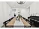 Bright dining room with piano, decorative chandelier, and modern furniture with view to entry and kitchen at 3326 Woodmont Dr, Parrish, FL 34219