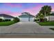 Charming blue two-story home with a two-car garage, lush lawn, and mature palm trees at sunset at 3326 Woodmont Dr, Parrish, FL 34219