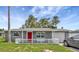 Charming single story home featuring a red door, picket fence, and well manicured lawn at 3426 Coldwell Dr, Holiday, FL 34691