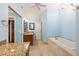 Bright bathroom featuring granite counters, travertine tile, large soaking tub, and blue walls at 3437 Aspen Trl, Clearwater, FL 33761