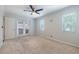 Bright bedroom featuring neutral carpet, ceiling fan, two windows and doors to the exterior patio at 3437 Aspen Trl, Clearwater, FL 33761