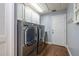 Laundry room boasts white cabinets, a modern washer and dryer, hardwood floors and a white door at 3437 Aspen Trl, Clearwater, FL 33761